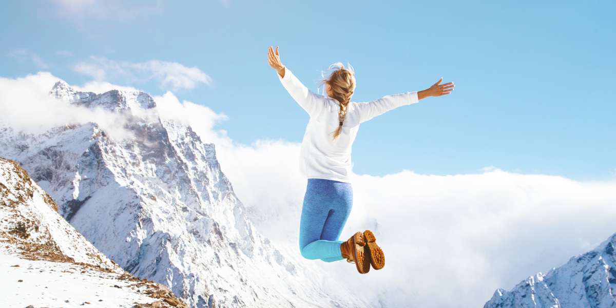 woman jumping on top of a mountain