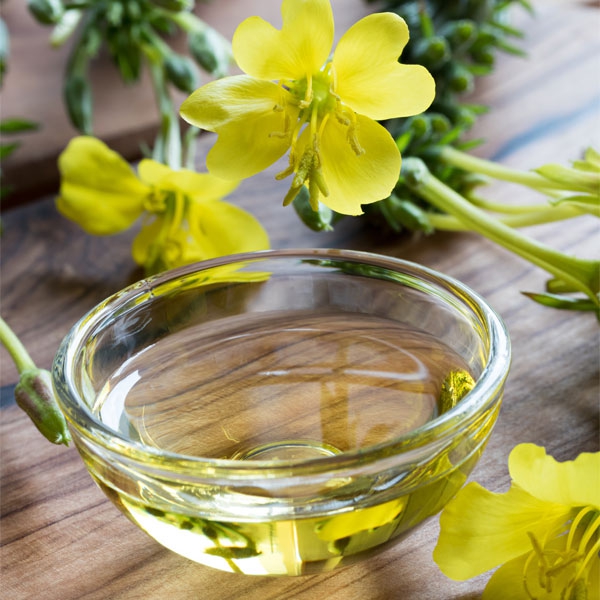 Fresh evening primrose flowers next to a bowl of evening primrose oil